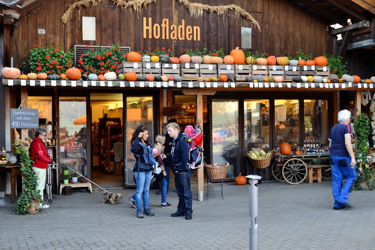 Hofladen mit Holzfassade, Kürbissen und Kisten vor dem Eingang